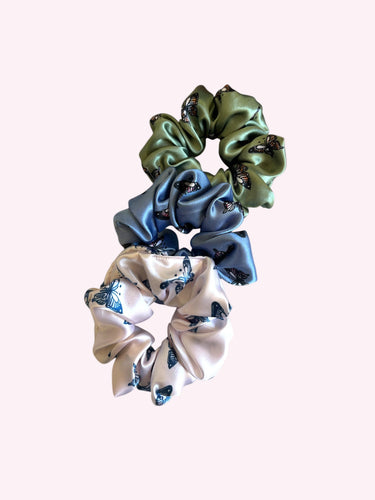 Three scrunchies in green, blue, and white with floral pattern on a white background